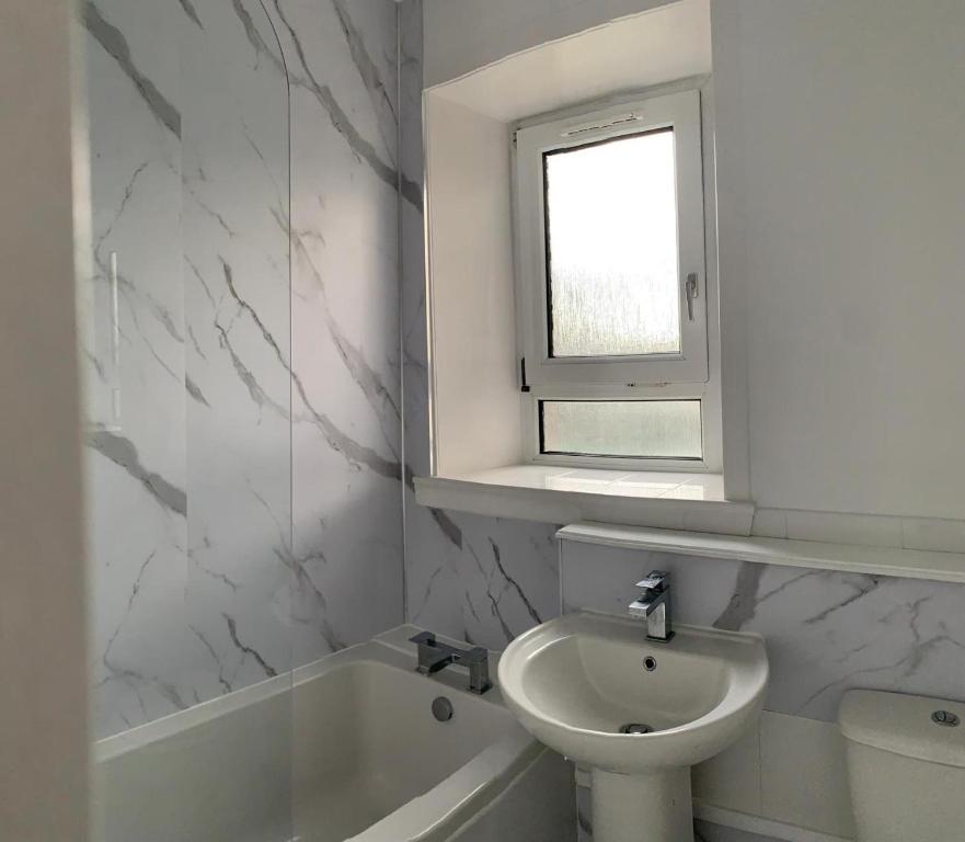 baño con lavabo y aseo y ventana en Beautiful 2-Bed Apartment in Aberdeen en Aberdeen
