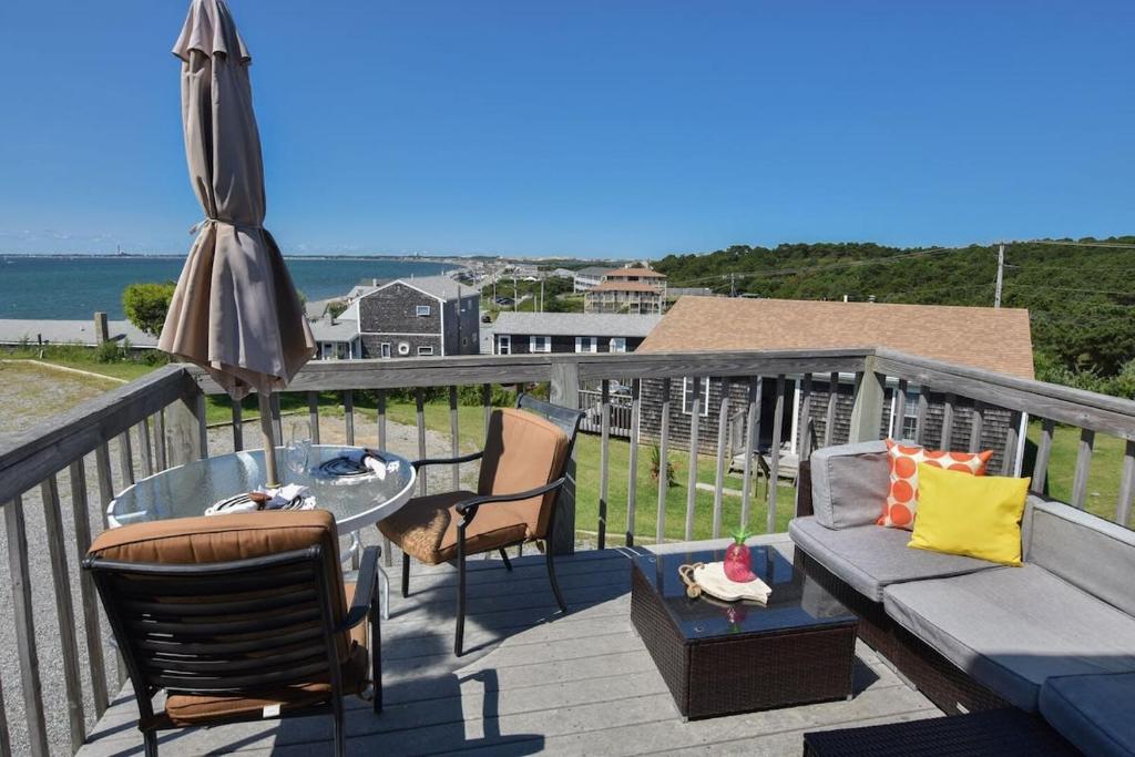 a patio with a couch and a table and an umbrella at 12215 - Beautiful Views of Cape Cod Bay Access to Private Beach Easy Access to P-Town in Truro