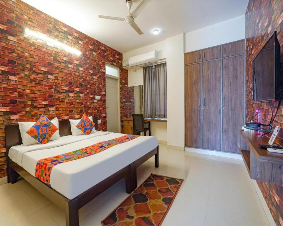 a bedroom with a bed and a brick wall at FabExpress Kings Suites in Bangalore
