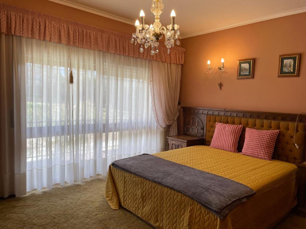 Cozy Guest House Albergaria في البرغاريا-ا-فلهه: غرفة نوم بسرير وثريا ونافذة