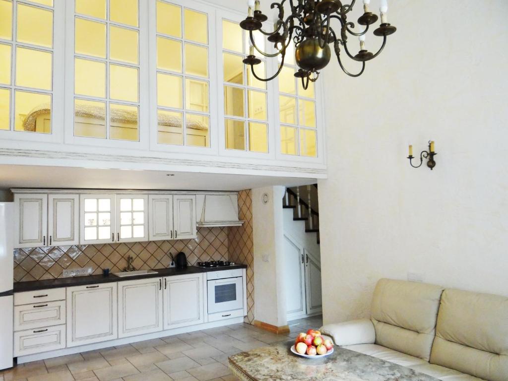 a kitchen with white cabinets and a couch in a room at Provence Home in Vilnius