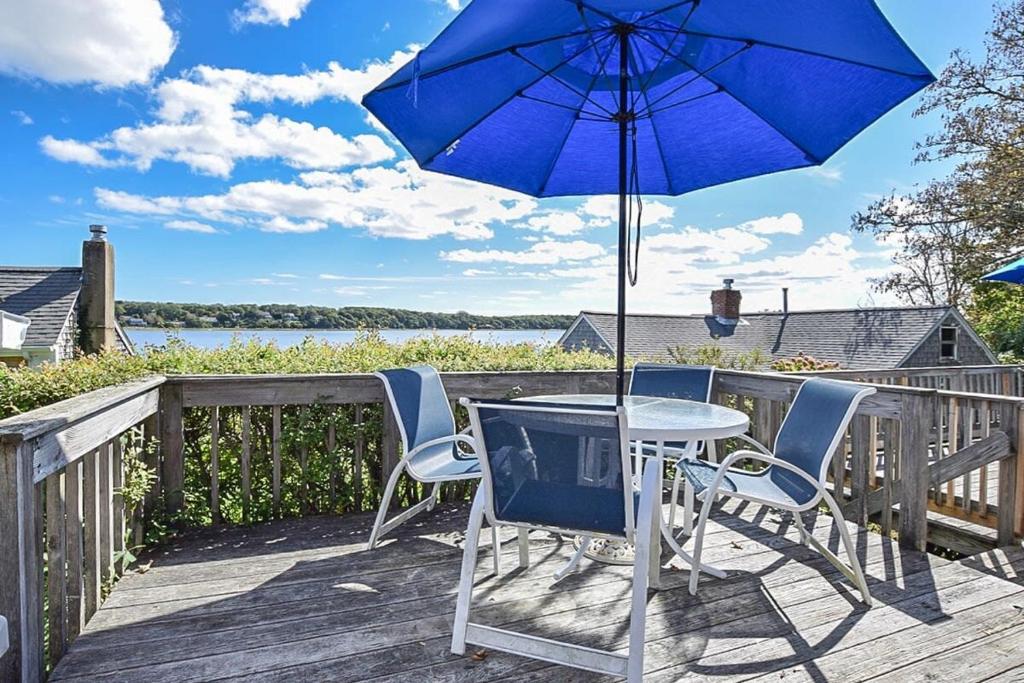 a table and chairs on a deck with an umbrella at Waterfront with Amazing views Dog Friendly in Eastham