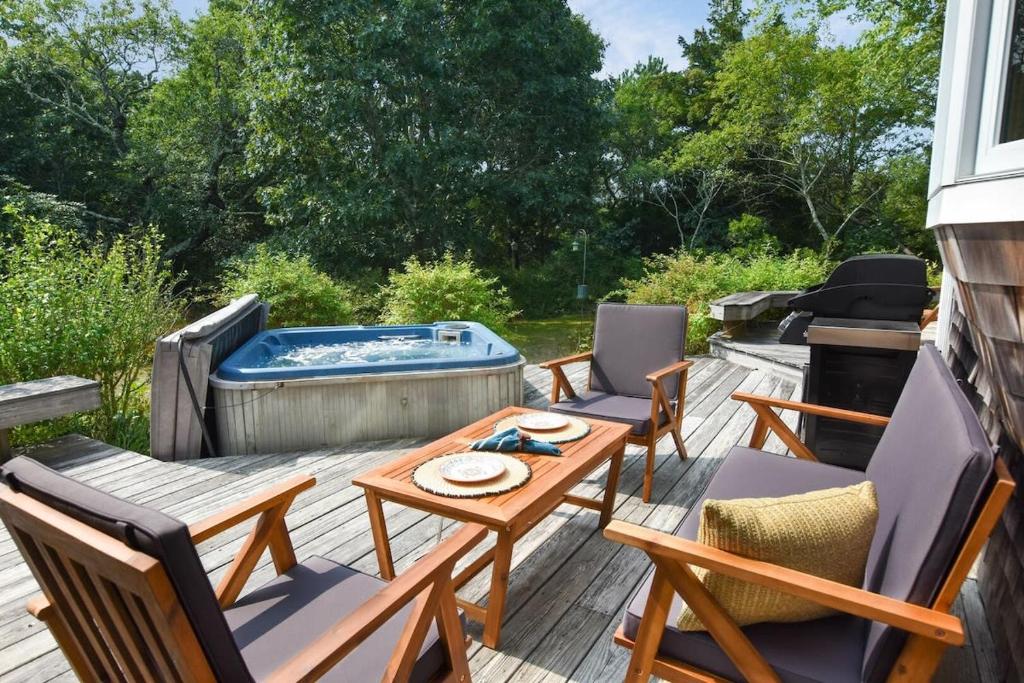 une terrasse avec des chaises, une table et un bain à remous dans l'établissement Walk to Water Hot Tub & Game Room, à Eastham