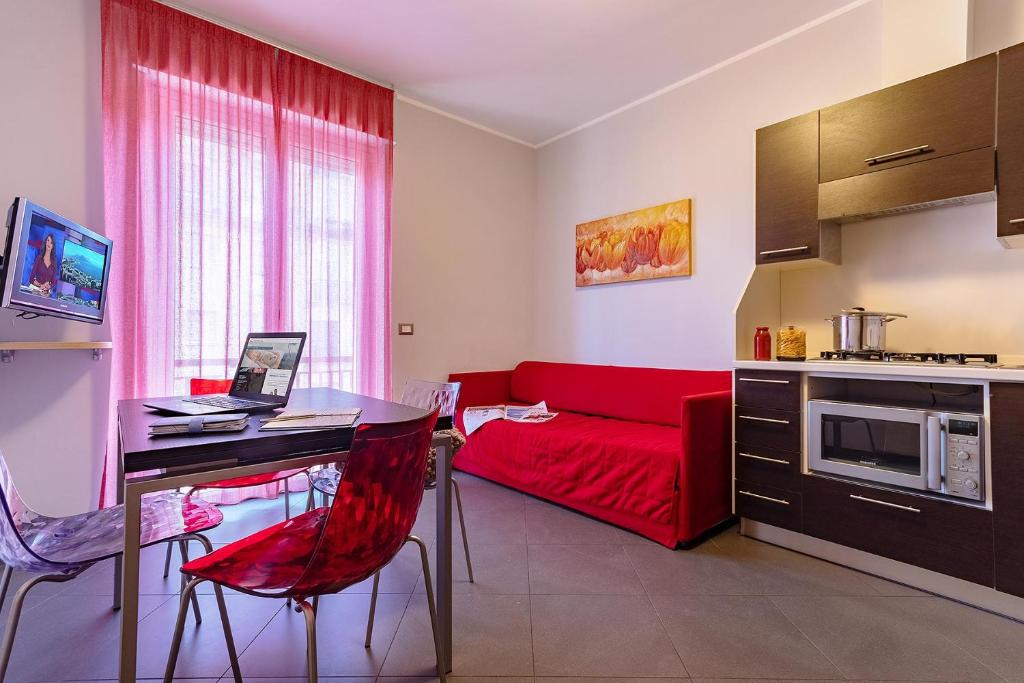 een woonkamer met een rode bank en een bureau bij Appartamenti Linda in San Bartolomeo al Mare