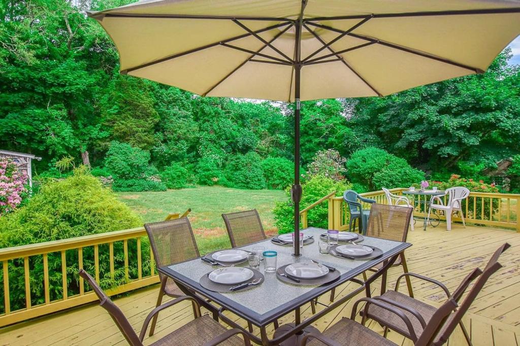 a table with an umbrella on a deck at 4-5 Min to Mill Pond or Nauset Beach in Orleans