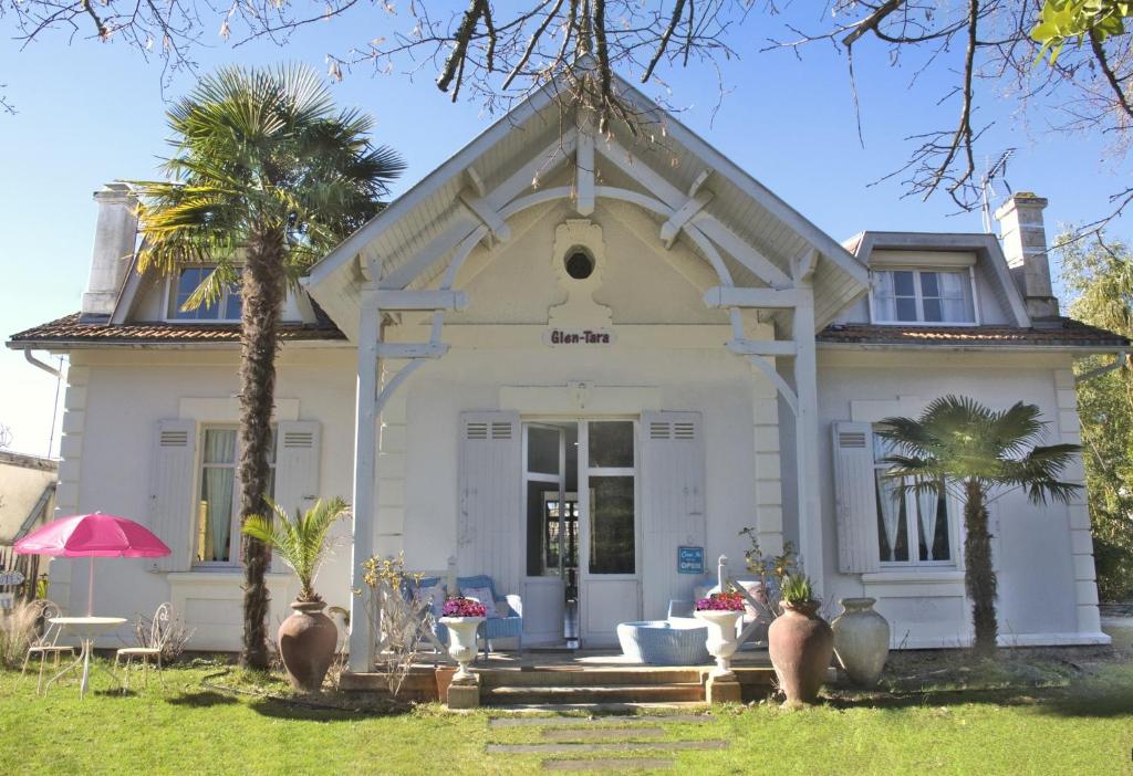 une maison blanche avec des palmiers devant elle dans l'établissement Villa Glen-Tara, à Lanton