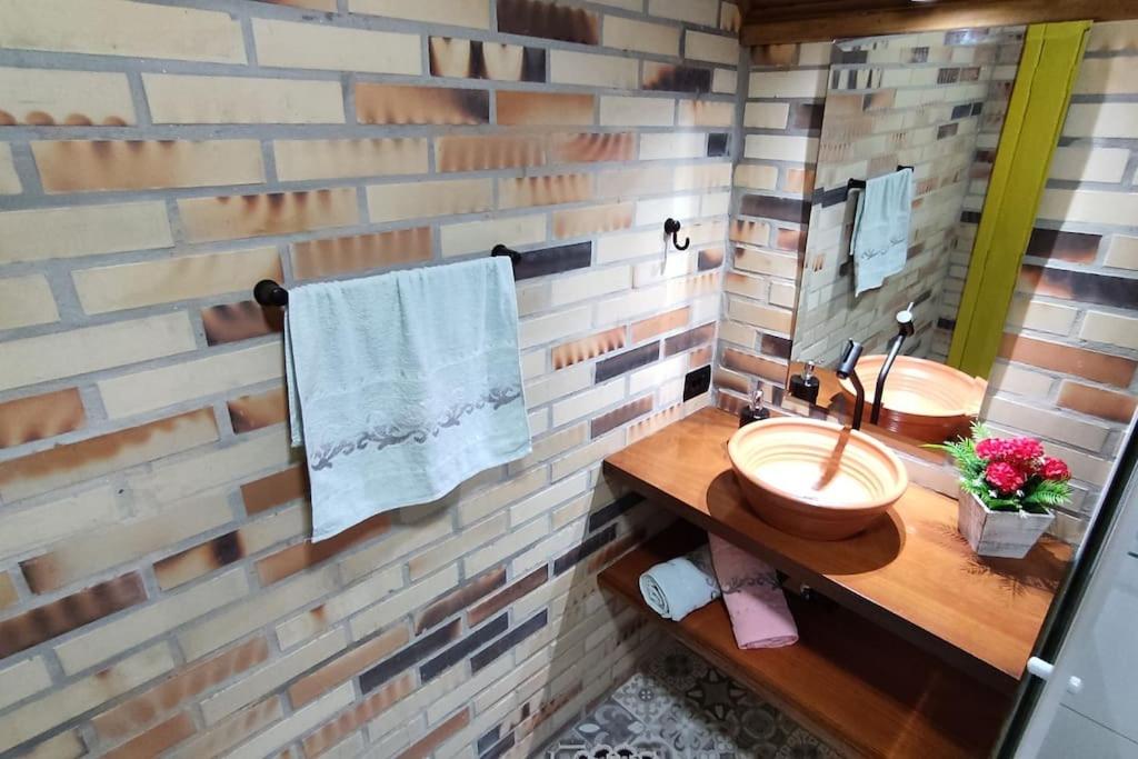 uma casa de banho com 2 lavatórios e uma parede de tijolos em Chalé do Vale Pomerode em Pomerode