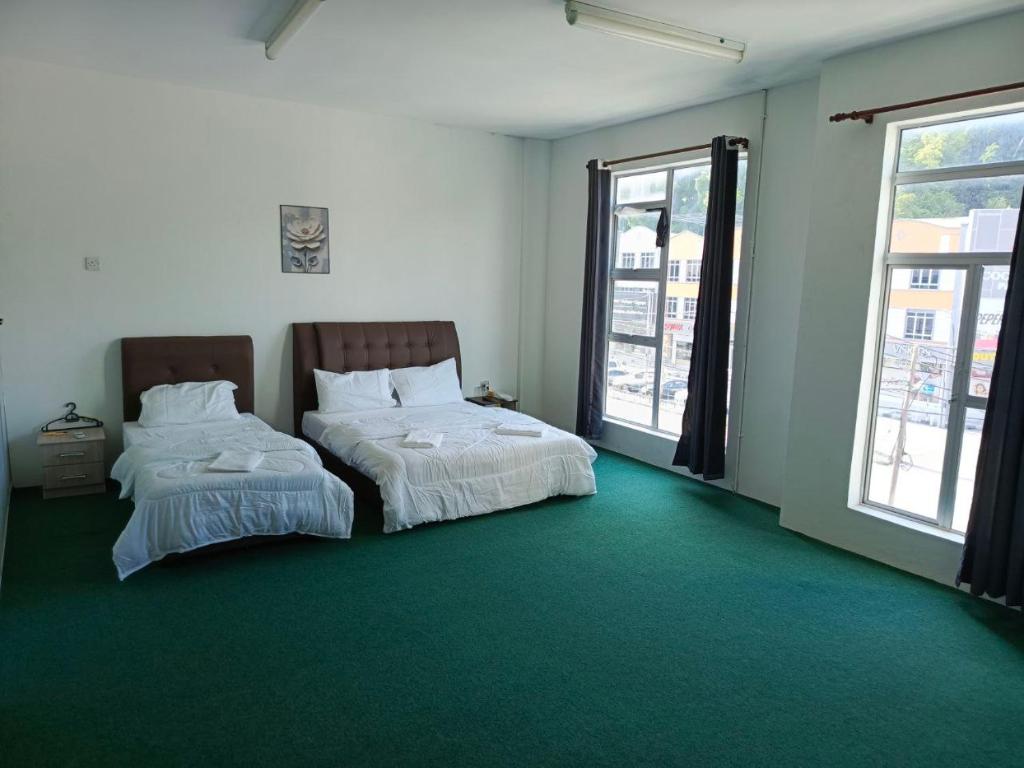 two beds in a room with green carpet at HASD GUESTHOUSE PANGKOR in Pangkor