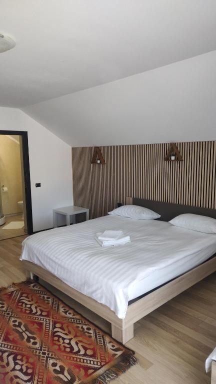 a bedroom with a large bed with white sheets at Vila Puiu Borsa MM in Borşa