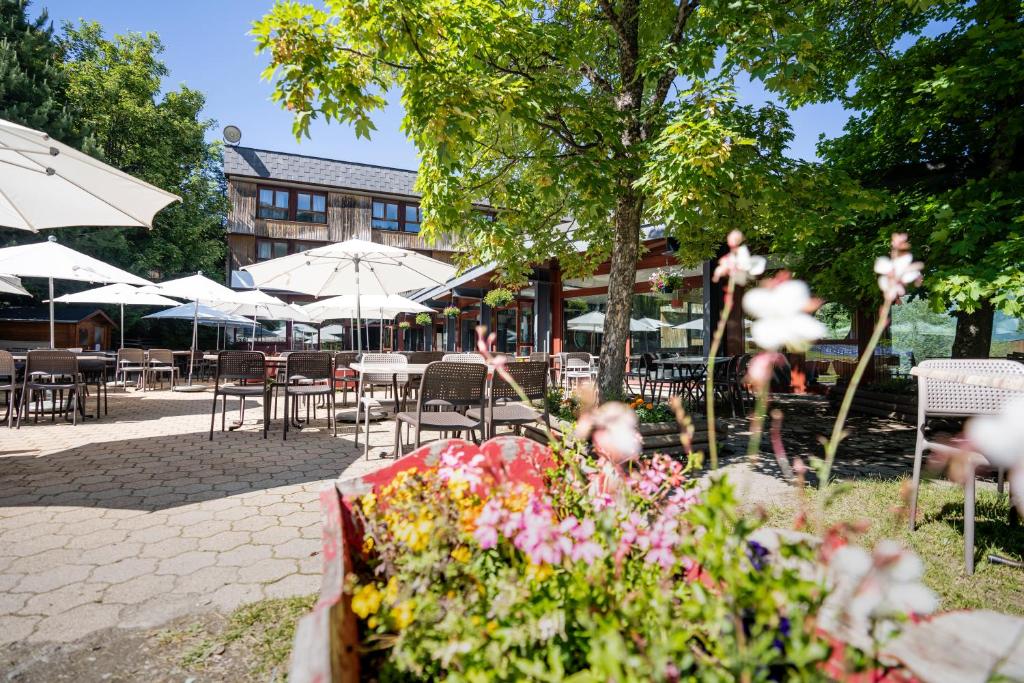 a patio with tables and chairs with flowers and umbrellas at Villages Clubs du Soleil - LES KARELLIS in Montricher-Albanne