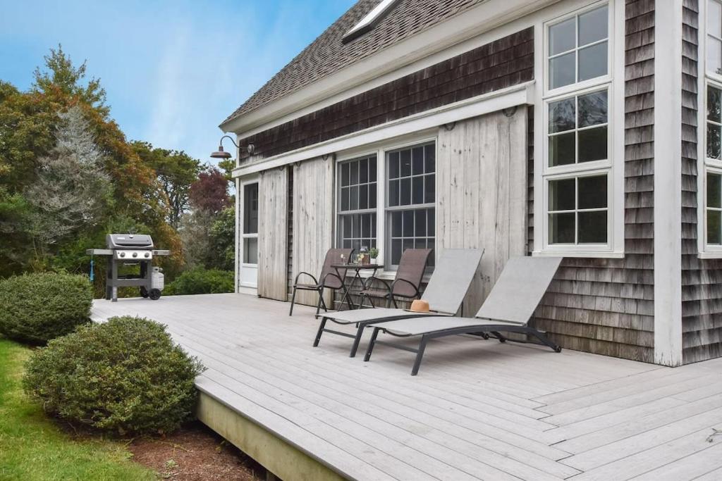 オーリンズにあるCentral A C Private Path to Nauset Beachの家の上に椅子とグリル付きのデッキ