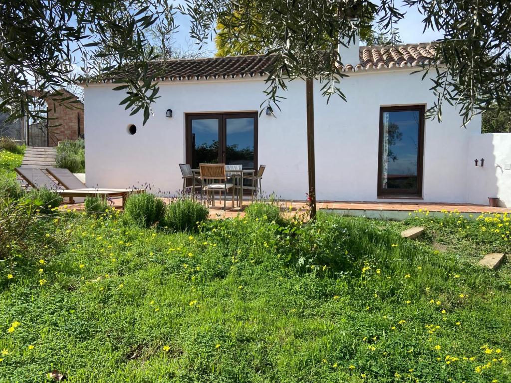 ein weißes Haus mit einem Tisch und Stühlen im Hof in der Unterkunft La colina buena - Eco retreat in Monda