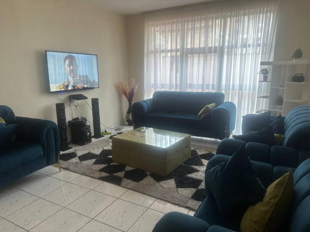 ein Wohnzimmer mit blauen Sofas und einem Flachbild-TV in der Unterkunft UNIQUE GUEST HOUSE in Addis Abeba