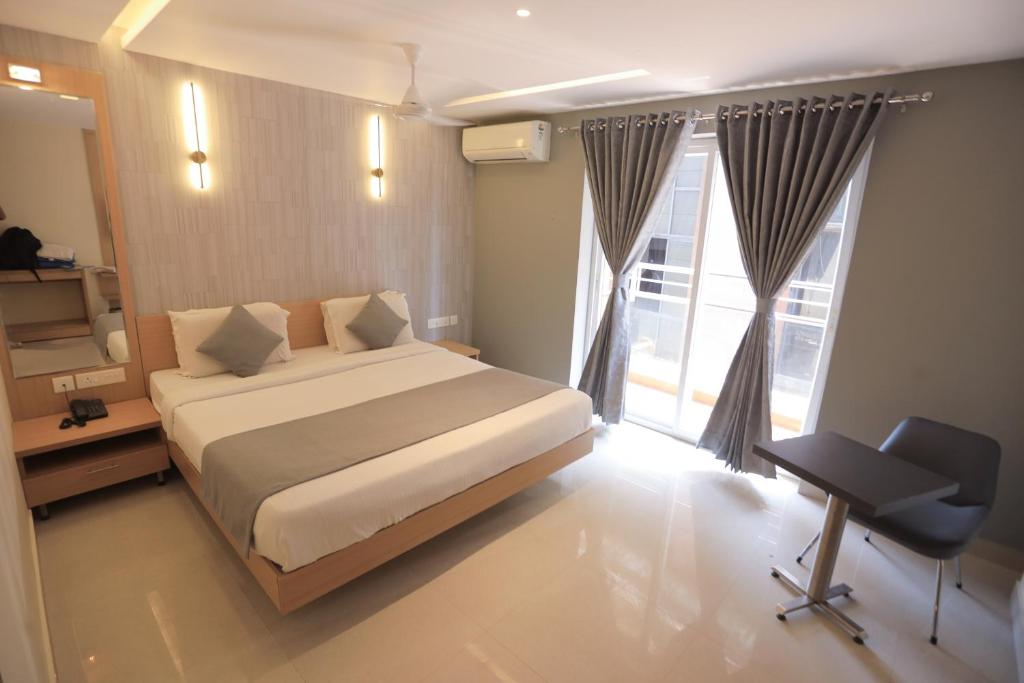 Hotel Shoolin Grand في منغالور: غرفة نوم بسرير ومكتب ونافذة