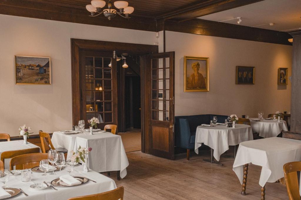 una sala da pranzo con tavoli e sedie bianchi di Brøndums Hotel a Skagen