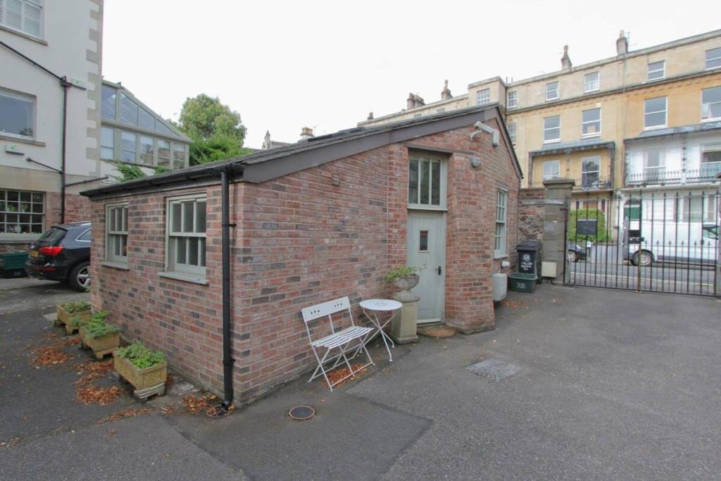 a small brick building with a chair in a parking lot at The Coach House, Clifton and Parking - Hopewell in Bristol