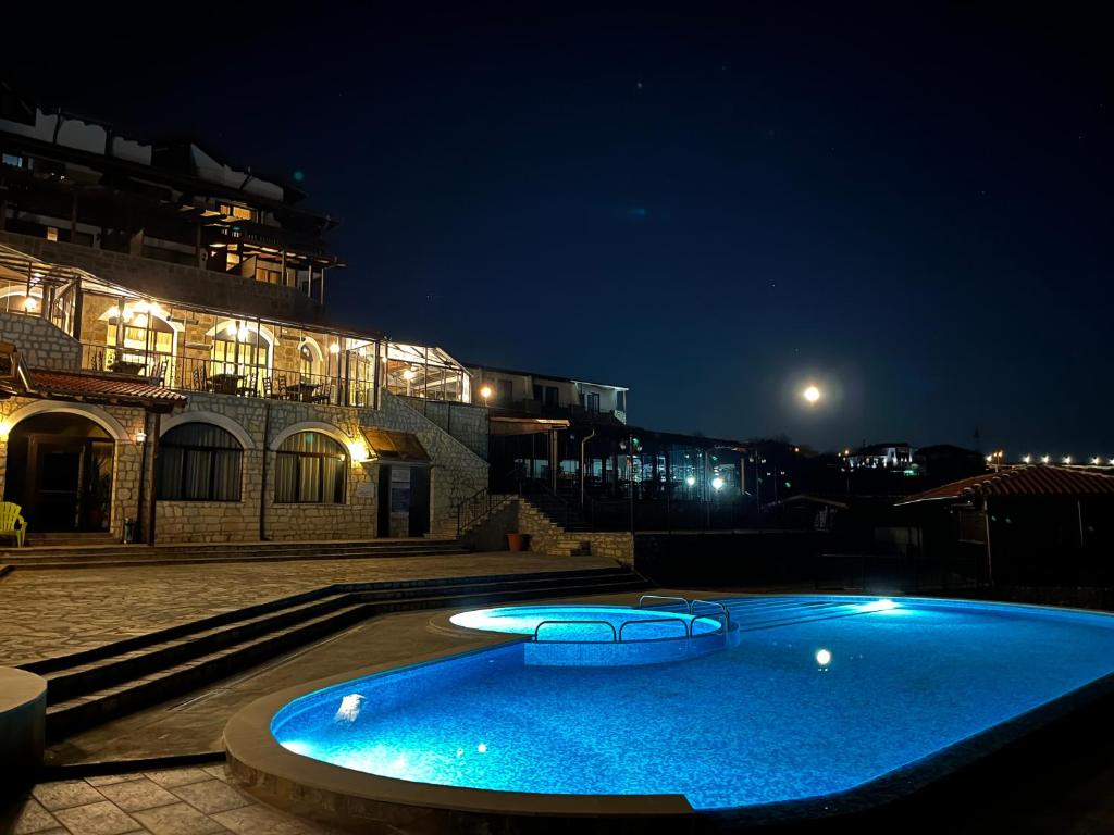a large blue swimming pool in front of a building at night at Complex Bolyarsko selo & Spa in Arbanasi