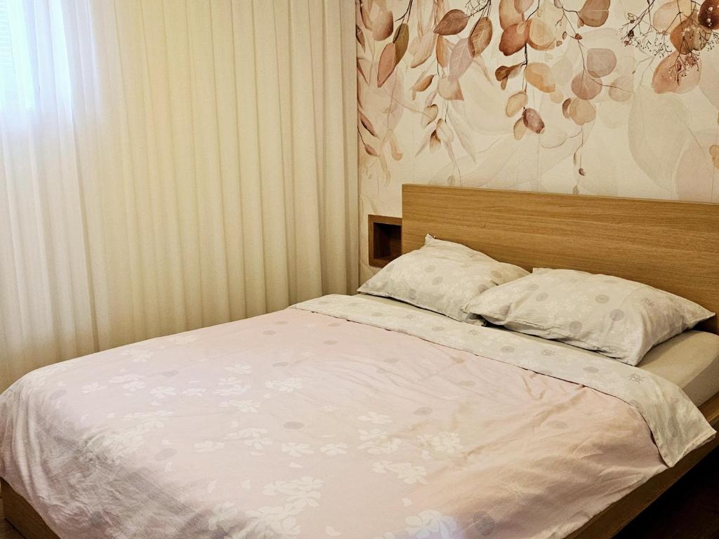Ce lit se trouve dans une chambre dotée d'un mur fleuri. dans l'établissement Apartma Kras, à Komen