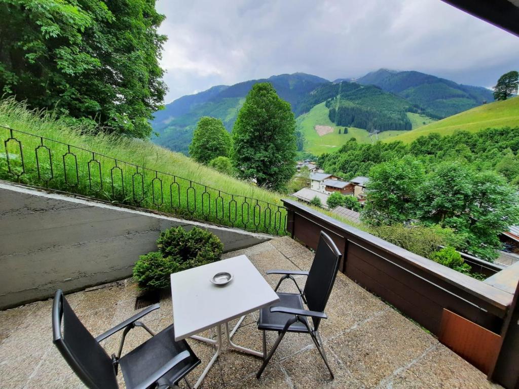 einen Tisch und Stühle auf einem Balkon mit Bergblick in der Unterkunft Appartement Bernkogel in Saalbach-Hinterglemm