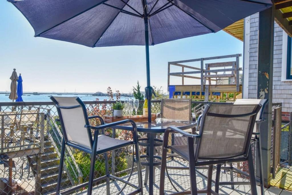 a table and chairs under an umbrella on a balcony at Gorgeous water views in the center of town in Provincetown