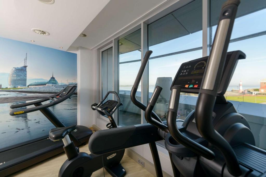 a gym with two elliptical machines and a window at Atlantic Hotel Sail City in Bremerhaven