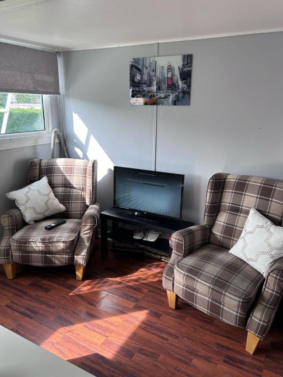 sala de estar con 2 sillas y TV de pantalla plana en Chalet 24 en Leysdown-on-Sea