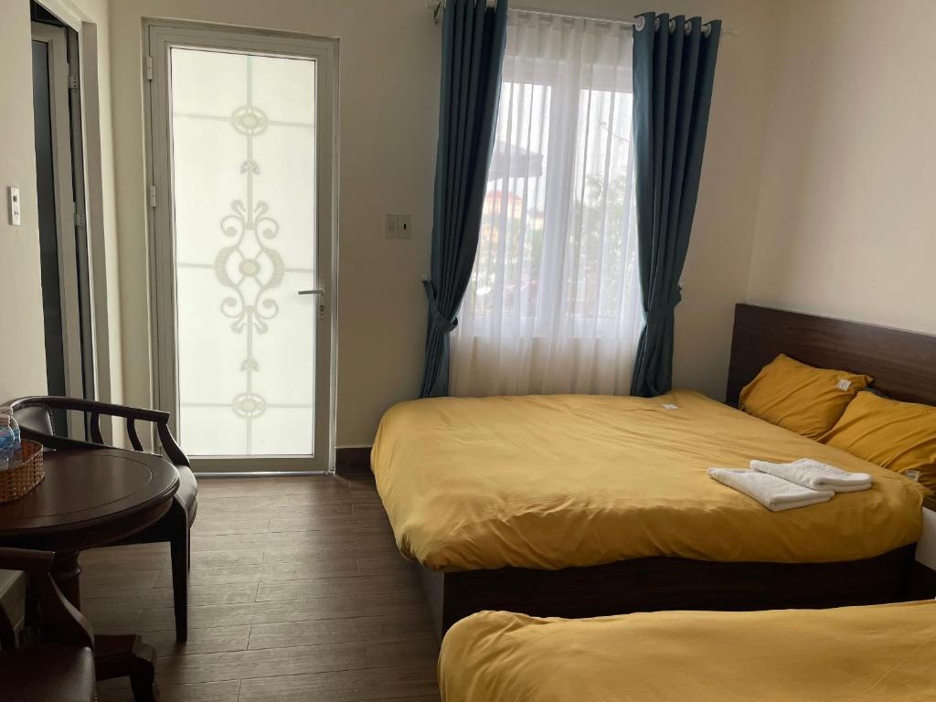 um quarto com 2 camas, uma mesa e uma janela em My House Hotel em Da Lat