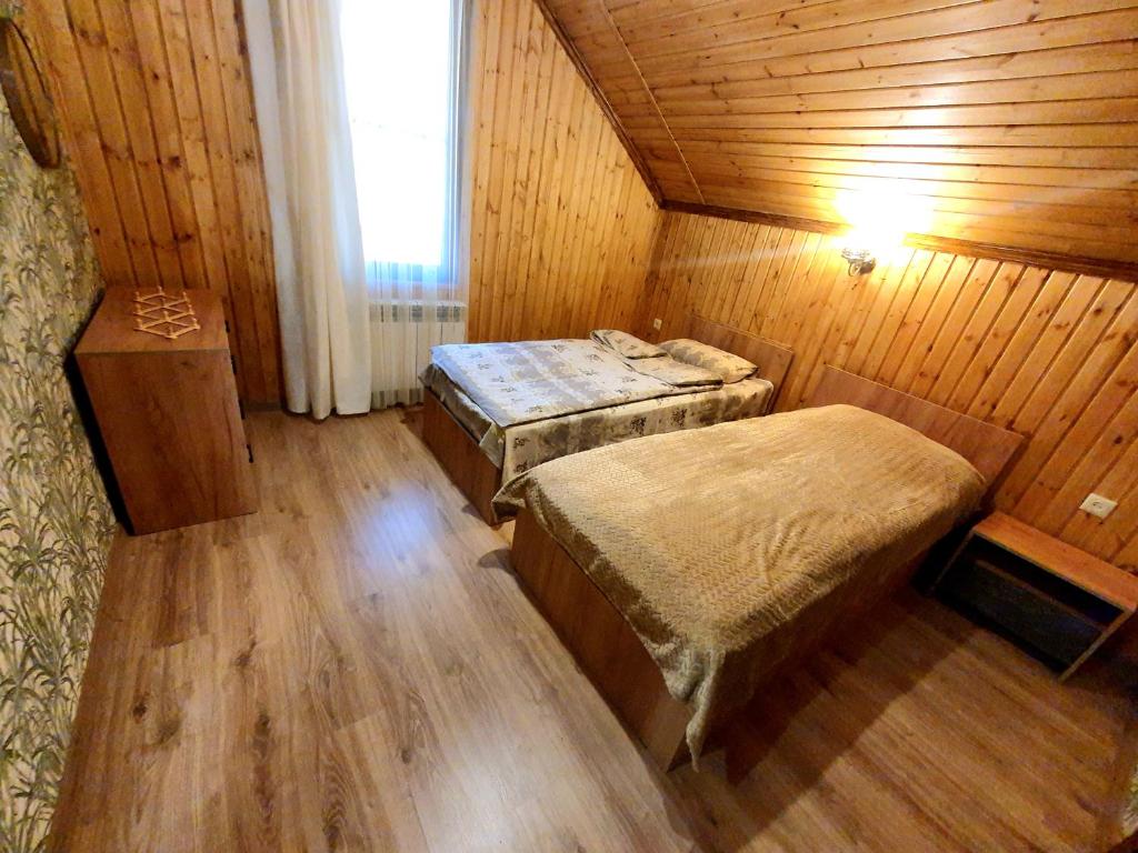 een slaapkamer met 2 bedden in een houten kamer bij Forest Gamp in Dilidzjan