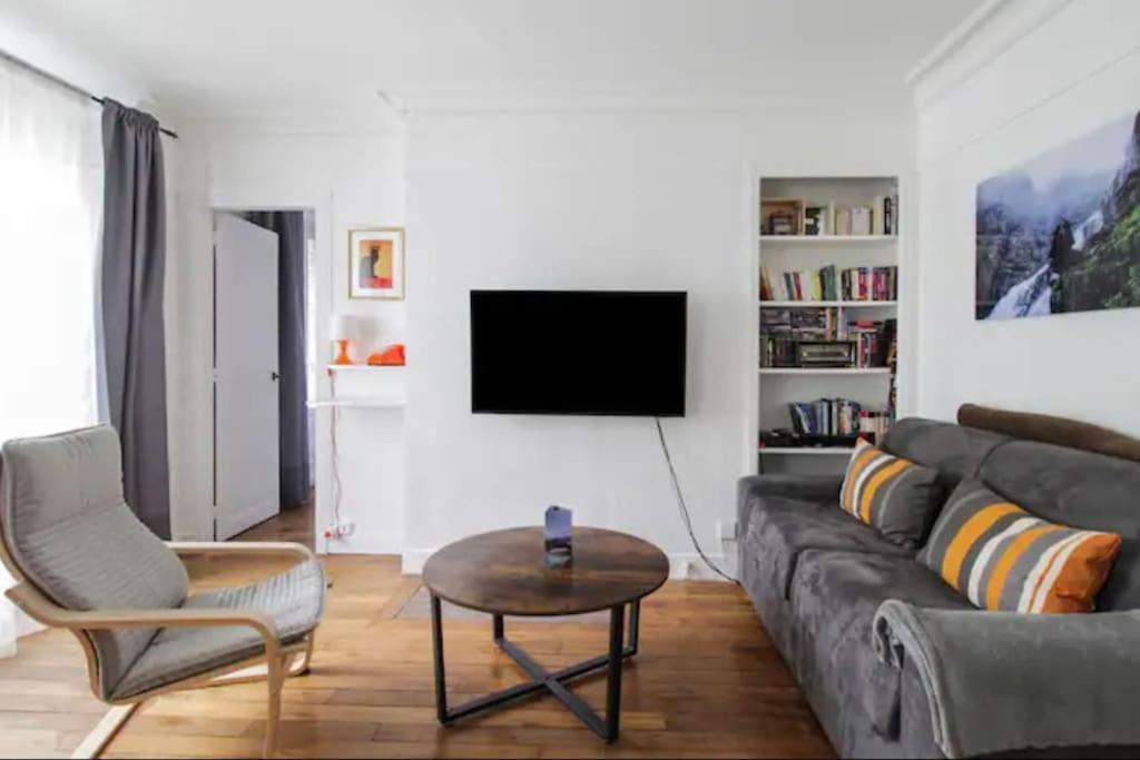 un salon avec un canapé, une table et une télévision dans l'établissement Charmant appartement à Paris, à Paris