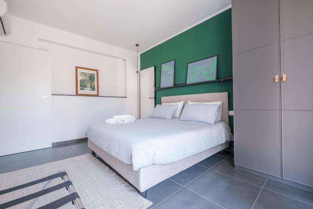 a bedroom with a white bed and a green wall at Ninai Sea Holiday Apartment 2 in Furci Siculo