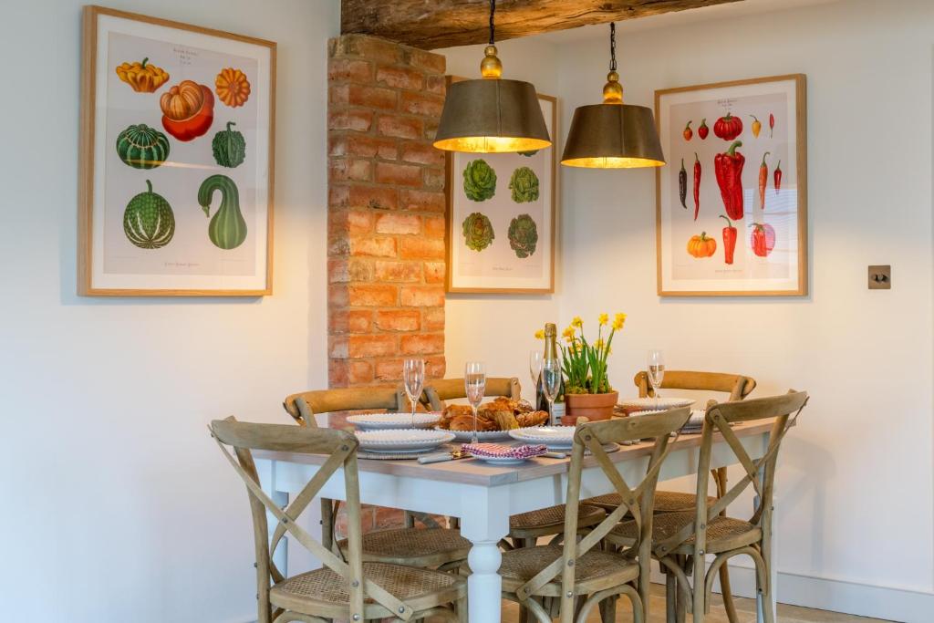 uma mesa de jantar com cadeiras e pinturas na parede em The Old Tractor Shed em Cheltenham