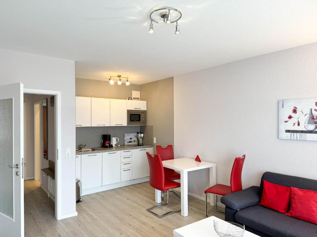 ein Wohnzimmer mit einem Sofa und einem Tisch mit roten Stühlen in der Unterkunft Haus Nordseeblick Wohnung 9 in Büsum