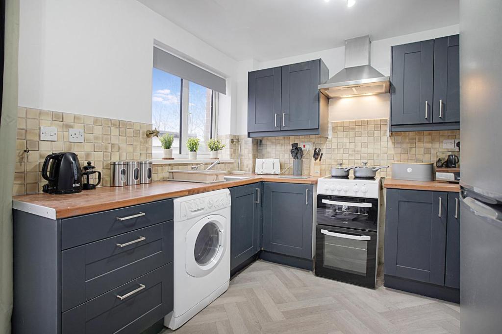 a kitchen with blue cabinets and a washing machine at Deerness Viewpoint-Your Scenic Retreat in Brandon in Durham