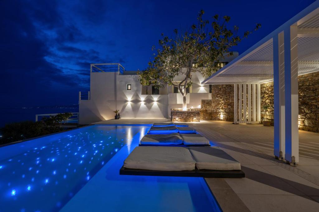 a villa with a swimming pool at night at Numi Suites in Mikonos