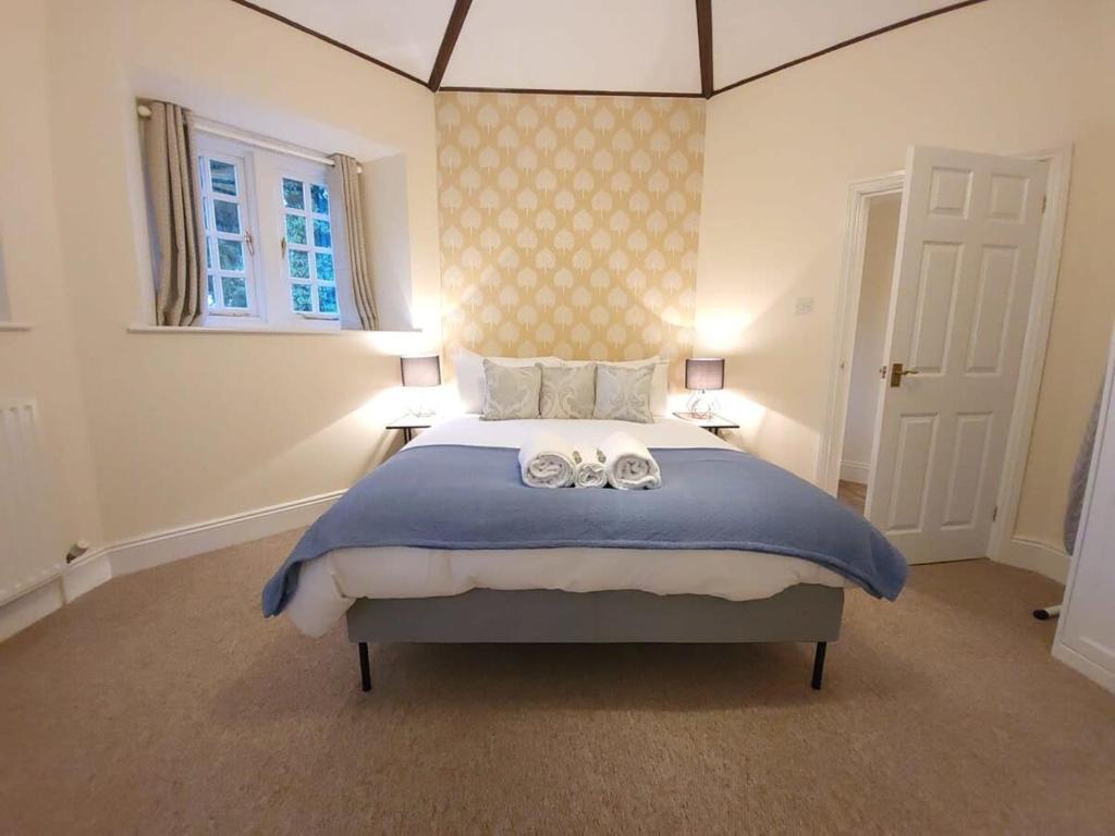 a bedroom with a large bed with two towels on it at Cosy 1-bedroom cottage next to Combe Lodge Venue in Blagdon