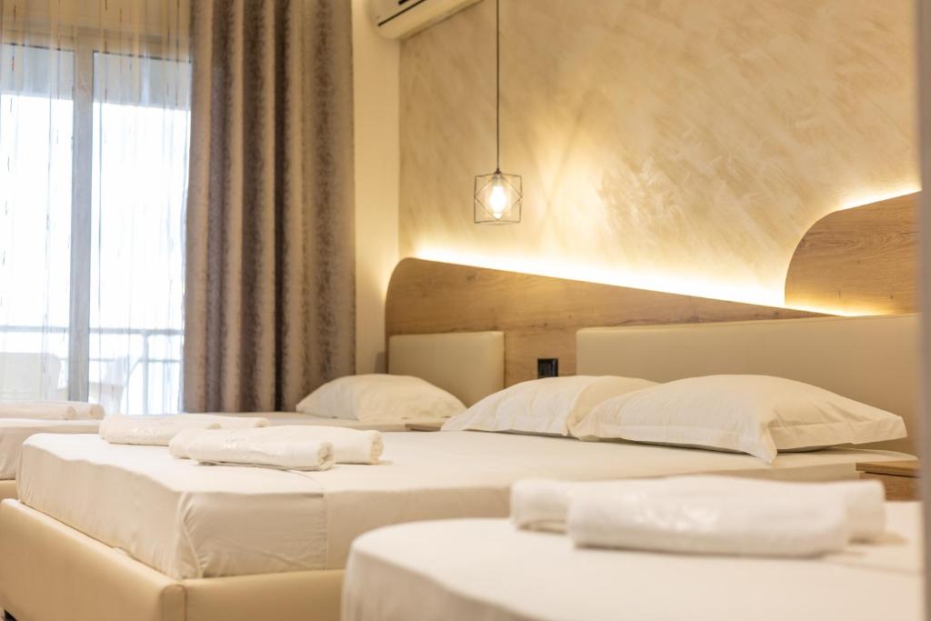 two beds in a hotel room with white sheets at Hotel Klebrido in Durrës