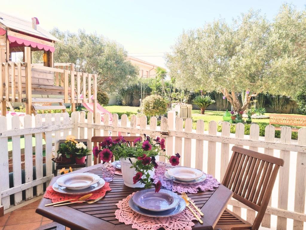 une table en bois avec des assiettes et des fleurs sur une clôture dans l'établissement Villa Calipso - Appartamento in Villa con giardino e wi-fi, à Ovile la Marinella