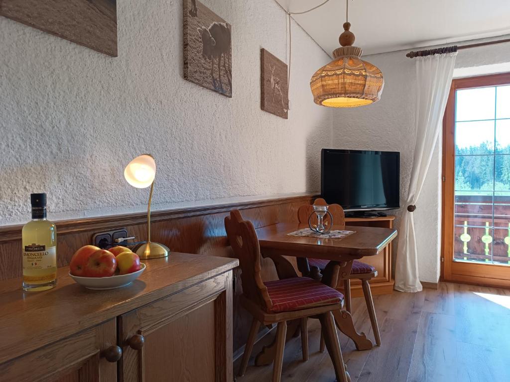 a kitchen with a table with a bowl of fruit and a television at Apartments im Jagdhof in Fischen