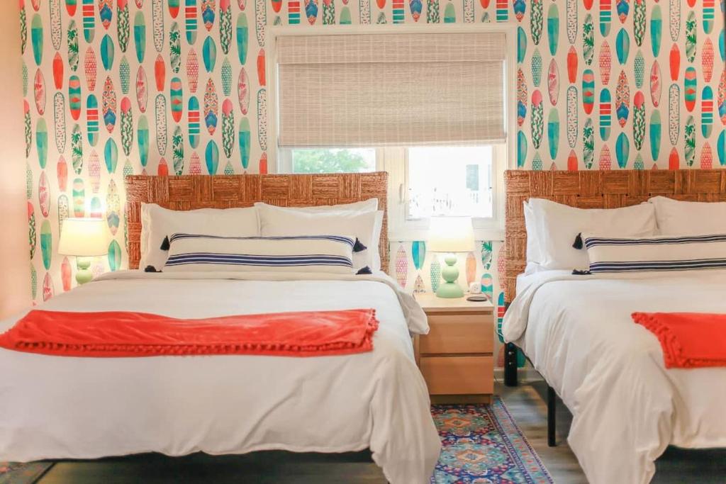 two beds in a bedroom with colorful wallpaper at Sojourn The Ocean Breeze in Virginia Beach in Virginia Beach