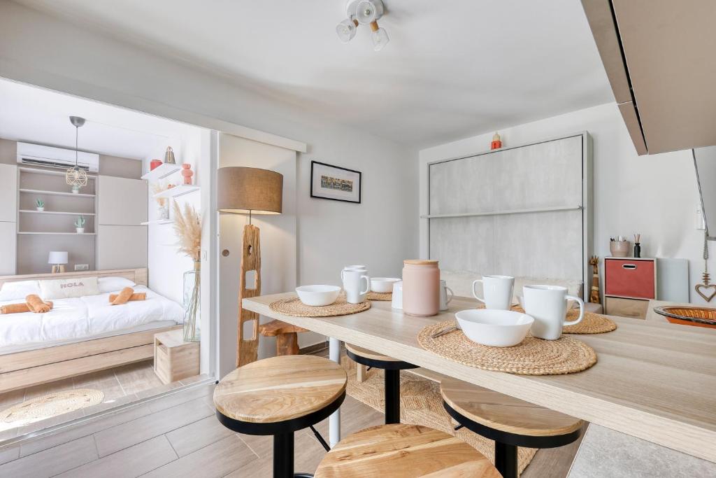 - une salle à manger avec une table, des chaises et un lit dans l'établissement L'Emeraude Varoise - Appt climatisé proche plage, à Six-Fours-les-Plages