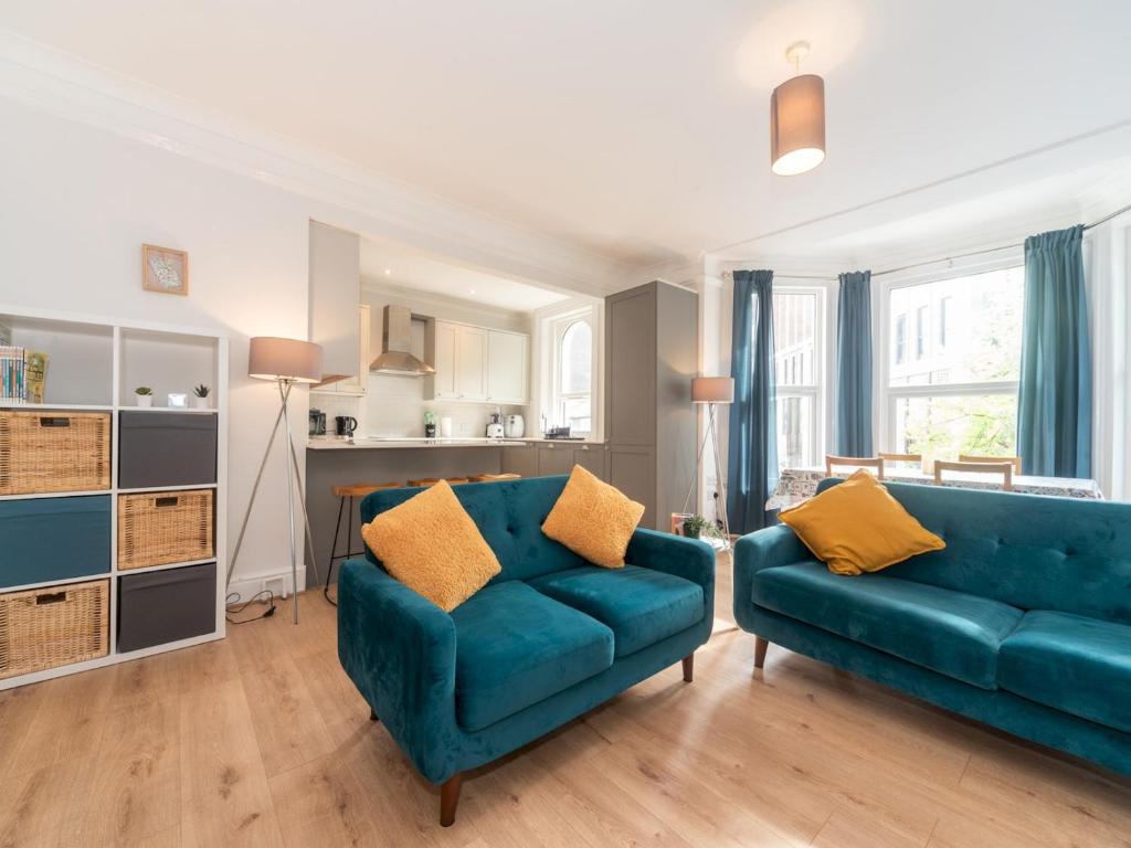een woonkamer met een blauwe bank en gele kussens bij Elegant bright flat free parking Pass the Keys in Kingston upon Thames