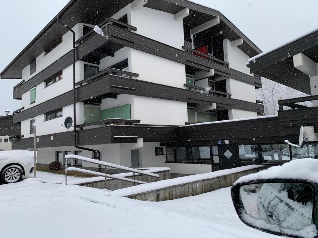 un bâtiment enneigé avec une voiture devant lui dans l'établissement Fereinwohnung Flussrauschen, à Kirchberg in Tirol