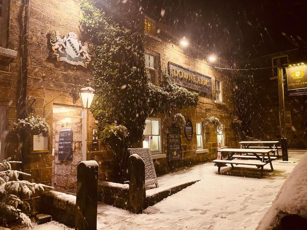 a building in the snow with a bench in front of it at The Downe Arms Hotel in Castleton