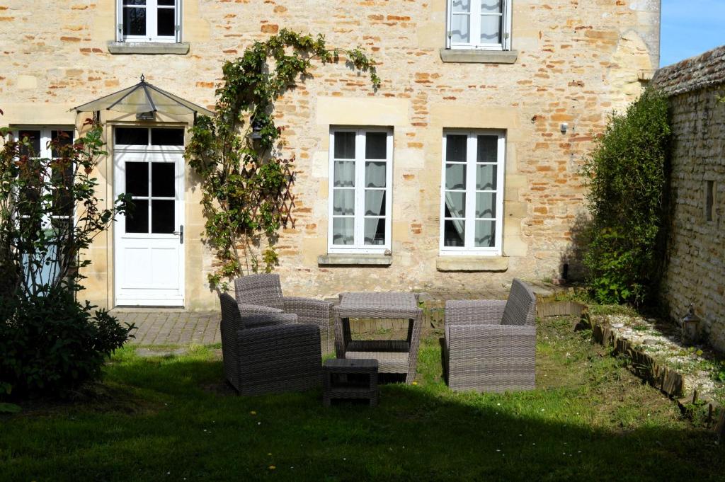 a patio with chairs and a table in front of a building at L'auberge du lavoir, maison en pierres avec jardin in Cairon