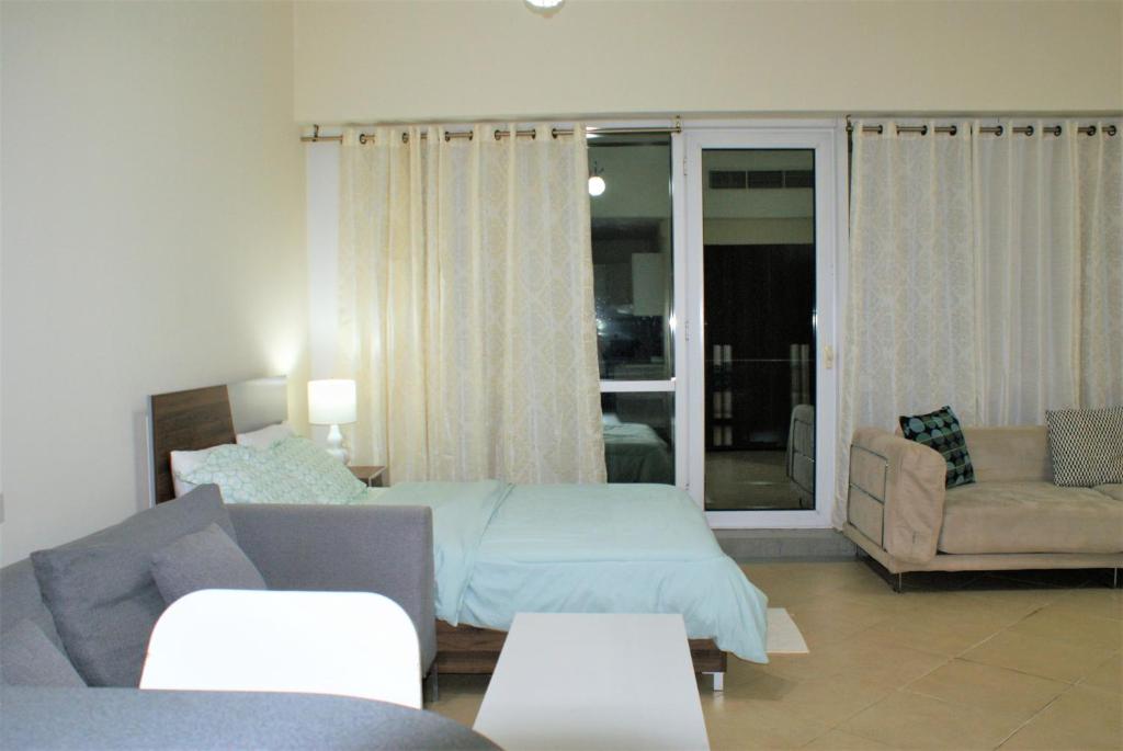 a bedroom with a bed and a living room with a couch at Studio Apartment - Cozy, Very Accessible and so near to Train Station in Dubai