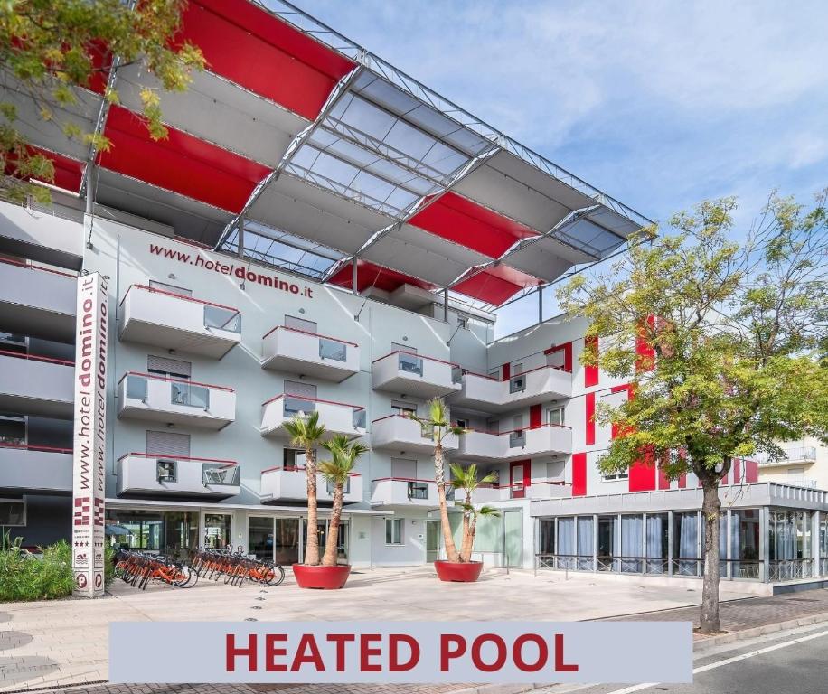 an apartment building with a heated pool on a street at Domino Suite Hotel & Residence in Lido di Jesolo