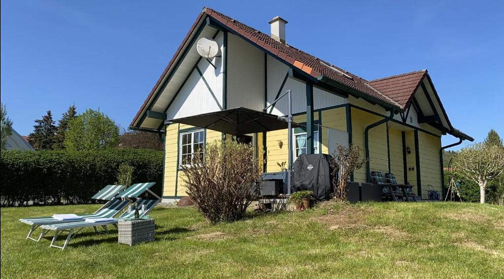 ein gelbes und schwarzes Haus mit zwei Stühlen davor in der Unterkunft Ferienhaus Wild Schlögl in Leutschach