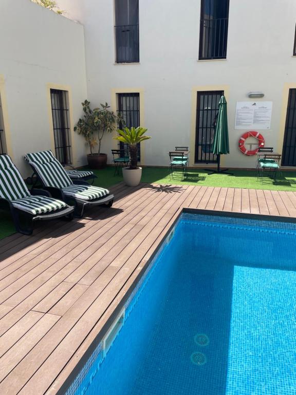 - une piscine avec 2 chaises à côté d'un bâtiment dans l'établissement Palacio de Luja, à El Puerto de Santa María