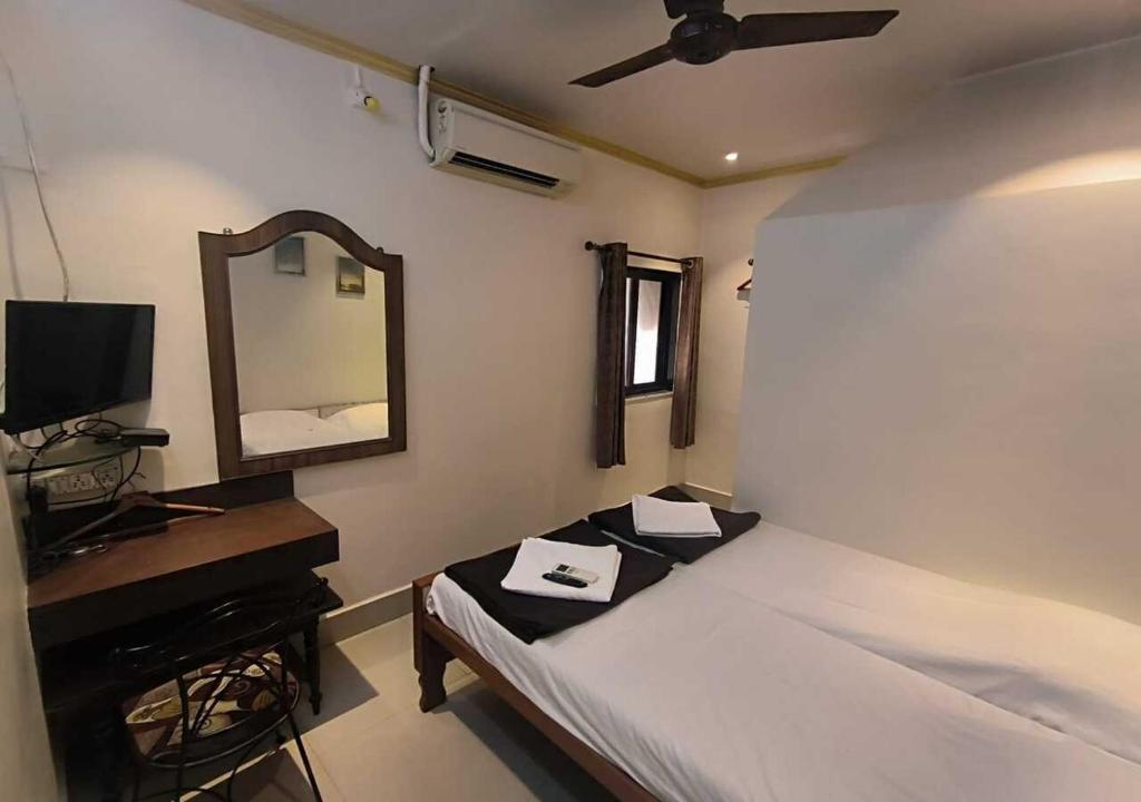 a bedroom with a bed and a mirror and a television at Hotel Rupali in Mumbai