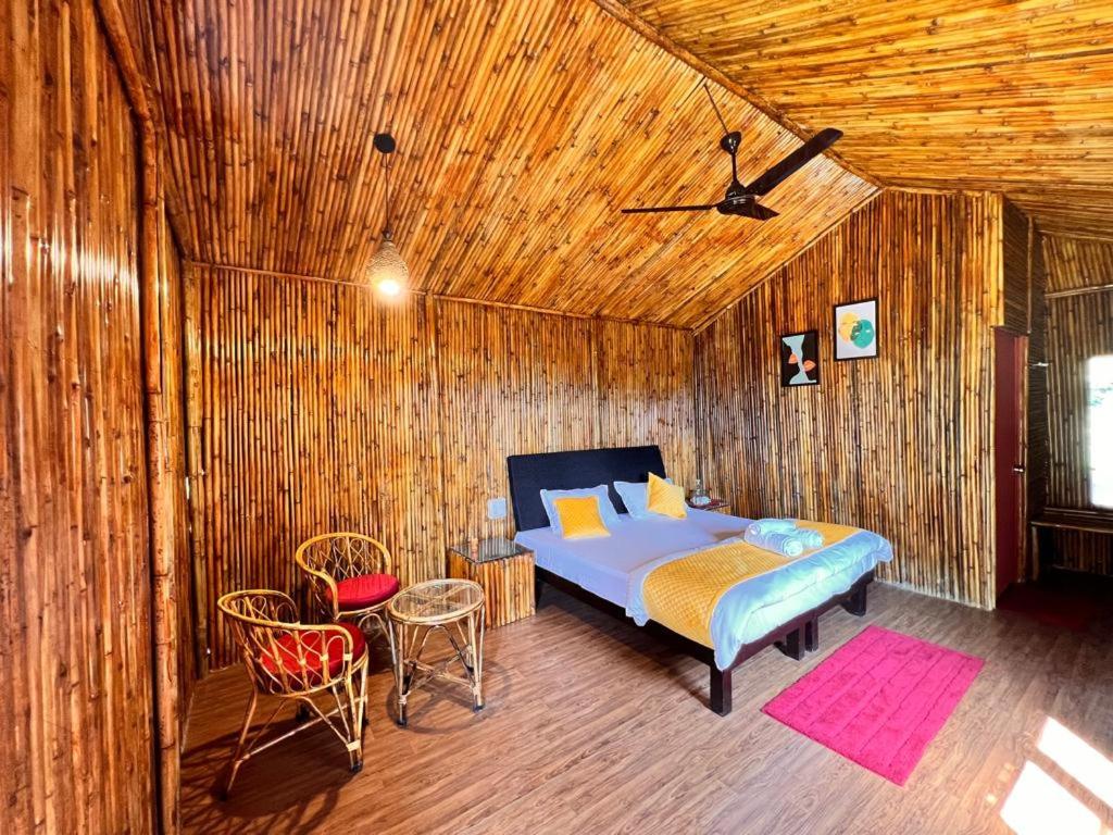 um quarto com uma cama e cadeiras numa parede de madeira em Romanchgiri Adventure Resort em Kāndi